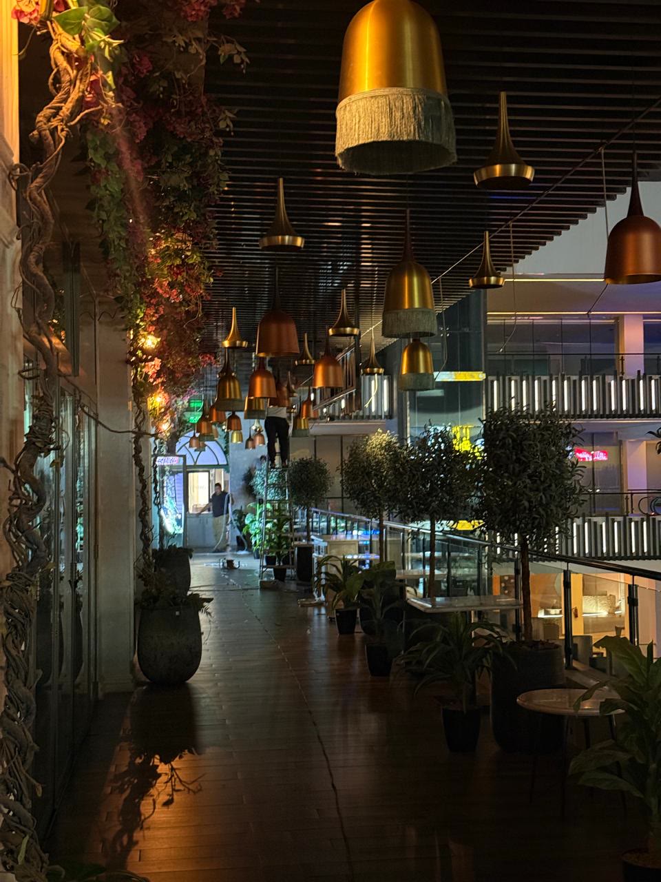 Villa Fayrouz Olaya renovation — brass pendant lights over a planted terrace walkway