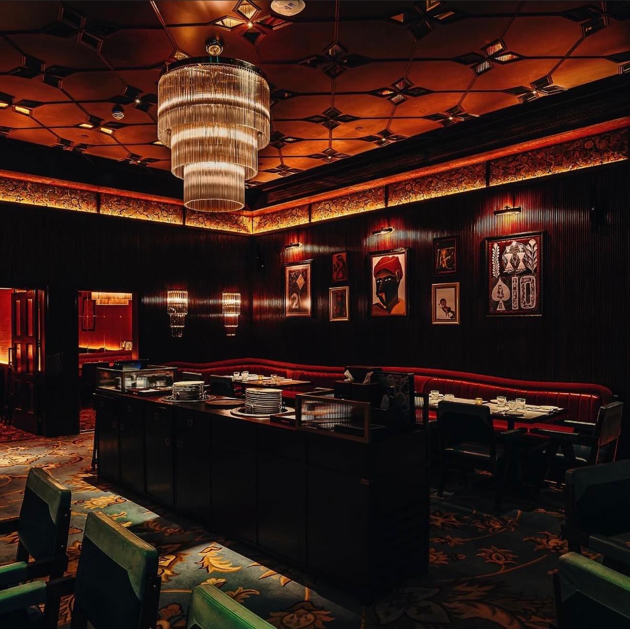 Gymkhana restaurant interior — dark wood panelling, patterned ceiling and chandelier